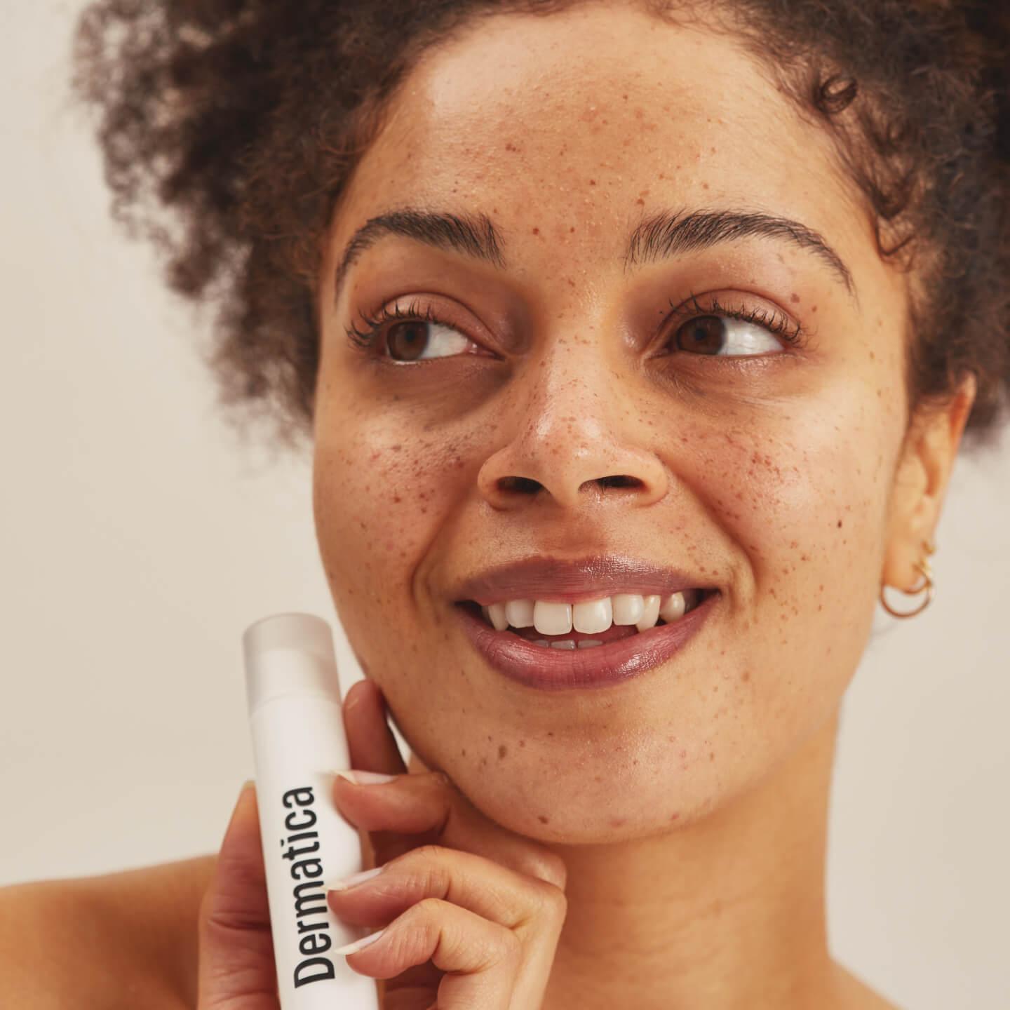 Smiling model holding a dermatica bottle