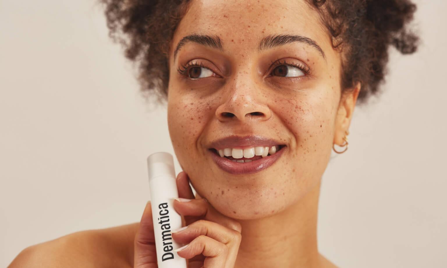 Smiling model holding a dermatica bottle