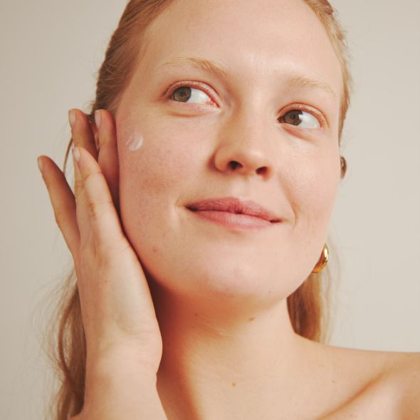 Woman face with applied cream on the cheek